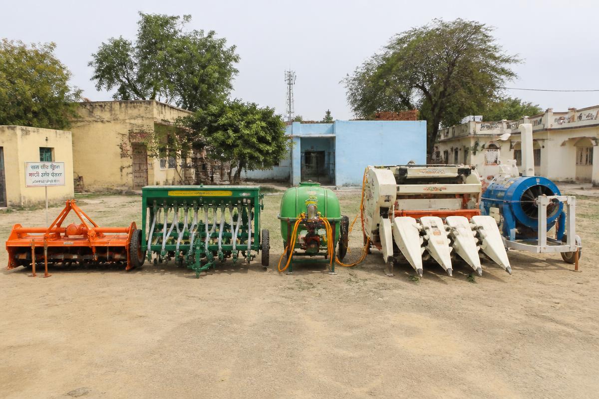 Rotavator, seed drill, sprayer and harvester attachments lined up at a village equipment bank